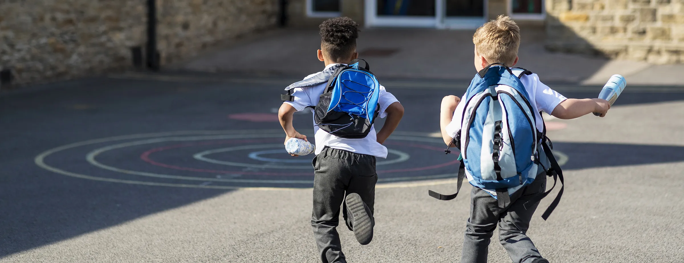 Two young children running into school